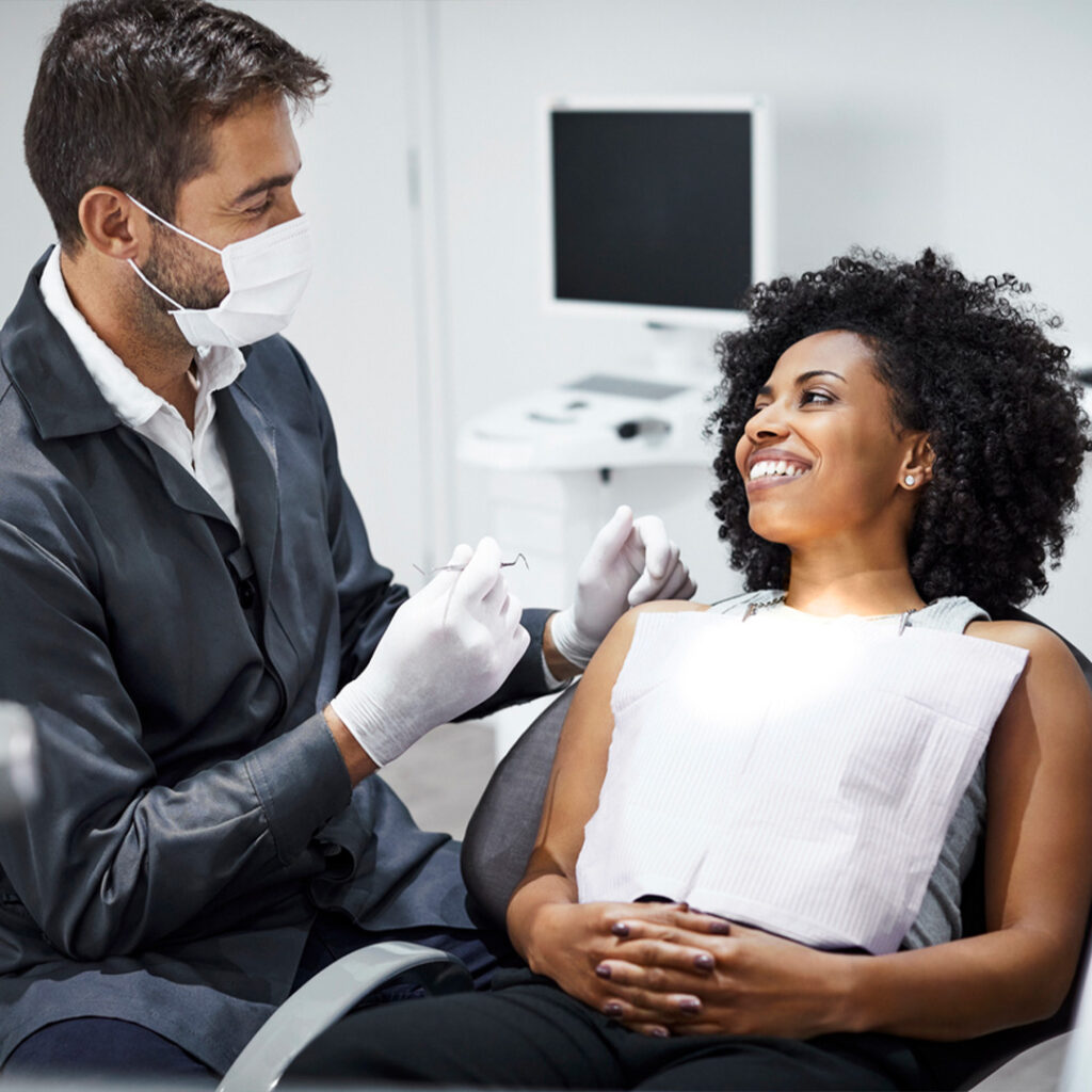 Dental clinic setting with a dentist attending to a patient in a dental chair, surrounded by dental equipment.